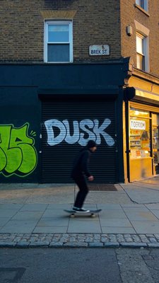 Skateboarder Passing by Colorful Graffiti at Dusk